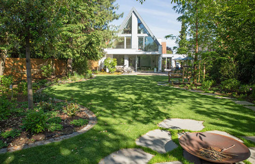Geschwungene Rasenfläche mit Blick auf Terrasse und Haus