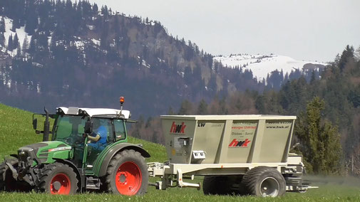 Bauer in einem Traktor, der gerade Steinsalz auf seinem Feld ausbringt