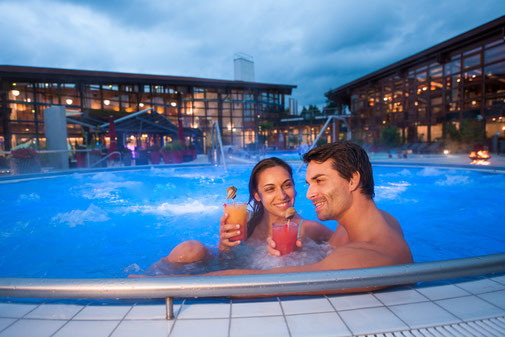 Badegäste mit Cocktail in der Therme Bad Steben bei Dämmerung