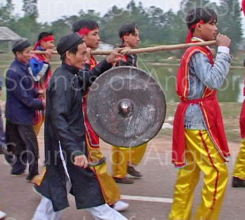 Gong in Vietnam during a procession. The musician holds the reverse V-link in order to limit the oscillation of the instrument.