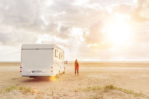 Wohnmobil am Strand im Sonnenlicht im Campingurlaub mit CDW-Versicherung der ERGO