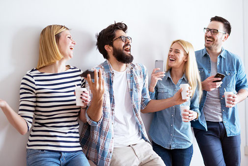 Junge Menschen mit Kaffeebecher und Handy in der Hand bei einem Tagesseminar gut versichert mit der ERGO Eintrittskarten-Versicherung