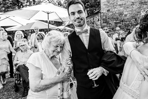 Photographe mariage Montauban – homme accompagnant une invitée âgée lors d’un moment de complicité pendant un mariage
