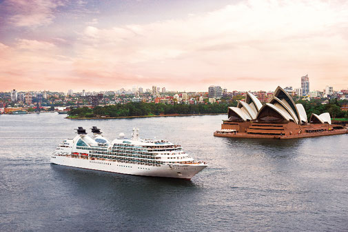 Das Oberdeck eines Seabourn Luxusschiffs mit mehreren Pools und bequemen Liegestühlen, umgeben von einer beeindruckenden Berglandschaft.