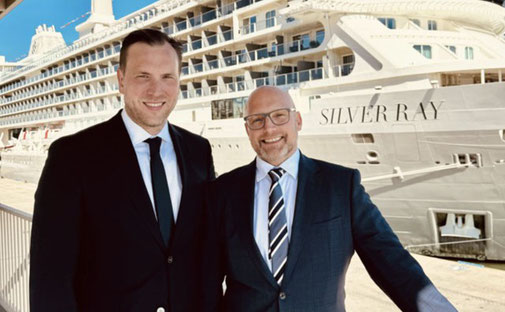 Nico Ruland und Timo Clarén im Anzug stehen lächelnd am Hafen vor der Silver Ray