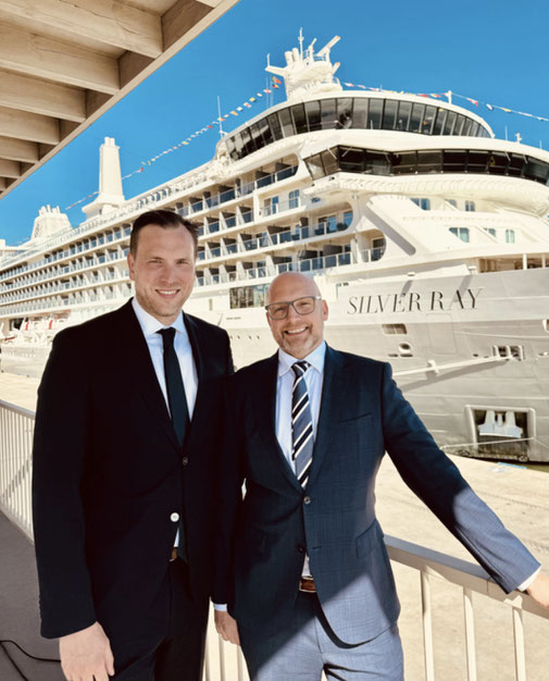 Nico Ruland und Timo Clarén im Anzug stehen lächelnd am Hafen vor der Silver Ray