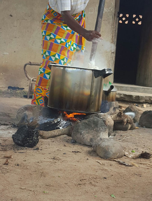 Eine malawische Frau, die eine bunte Chitenje trägt und Nsima kocht