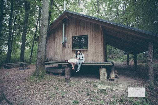 Ein Hochzeitspaar sitzt vor einem Holzhaus an der Hochzeitslocation Kletterpark des Outdoor Zentrums Lahnstein 