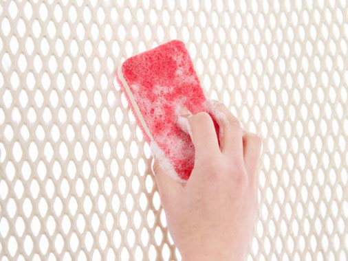 洗剤をつけたスポンジたわしでスノコを洗っている