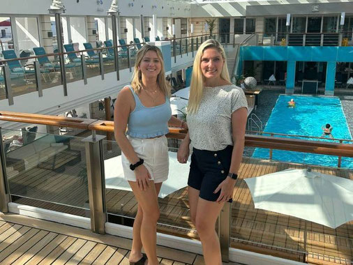 Anne Fischer und Nadine Erber von Emocean Cruises an Bord der EUROPA 2 auf dem Sonnendeck mit Pool im Hintergrund.