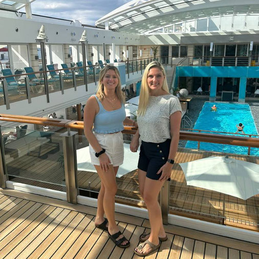 Anne Fischer und Nadine Erber von Emocean Cruises an Bord der EUROPA 2 auf dem Sonnendeck mit Pool im Hintergrund.