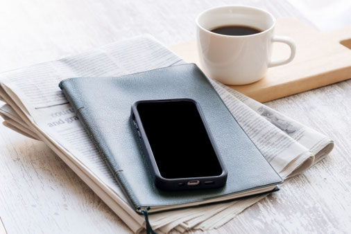 ノートパソコンの前に広げられた手帳。傍らにスマホ。