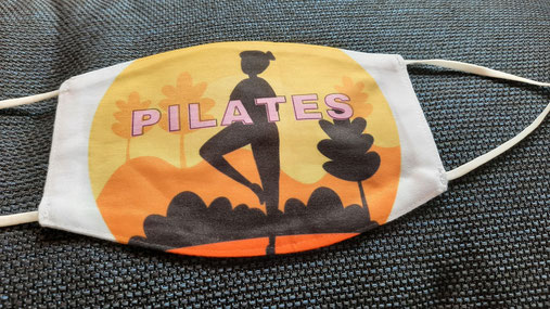 Pilates-Maske in Orange-gelb-Tönen mit schwarzer Figur und Aufschrift "Pilates"