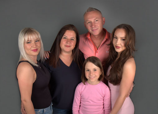Familienfoto im Studio von Photo Bergmeister in Stuttgart-Ost – fünf Personen lachen gemeinsam vor neutralem Hintergrund.