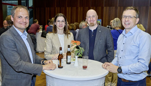 Vier Personen am Stehtisch, lachen und unterhalten sich