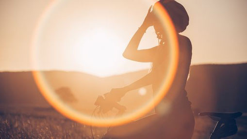 Silhouette einer Frau mit Fahrrad im Sonnenuntergang – Symbol für Achtsamkeit, Energie und innere Balance im Herbst.