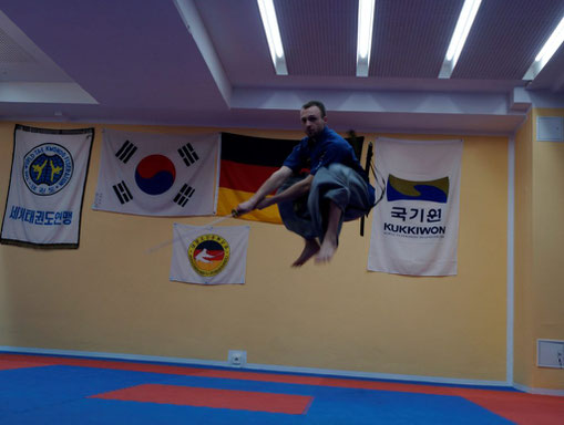 Heidong Gumdo-Meister spingt in die Luft und schlägt mit seinem Schwert.