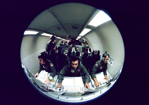 Inside an E-3 AWACS aircraft, radar controllers monitor fighters in an aerial battle.