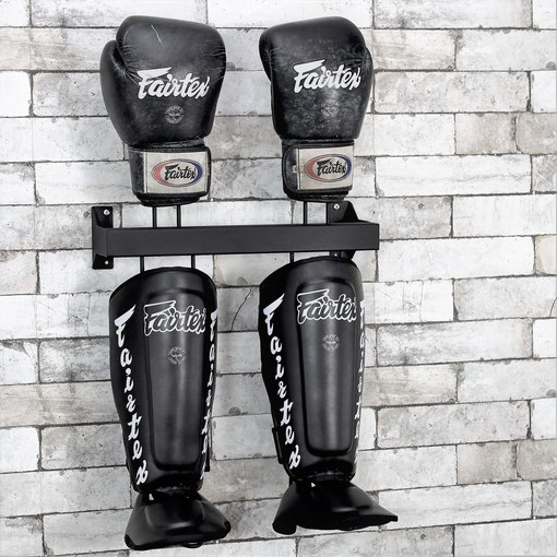  Fairtex black shinguard and boxing gloves rack on a brick wall