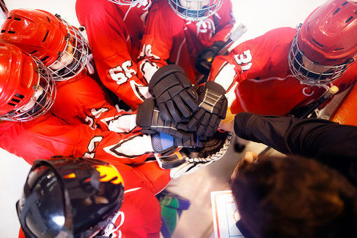 Eishockeyspieler kommen zusammen und bilden einen Kreis und halten die Hände zusammen