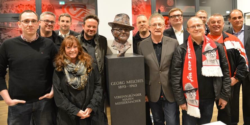Die Georg-Melches-Initiative und Unterstützer vor der Büste im Foyer des Stadions