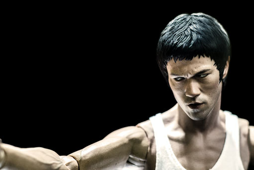 Auf dem Bild ist eine Action-Figur von Bruce Lee zu sehen. Das Bild ist in Schwarz-Weiß.