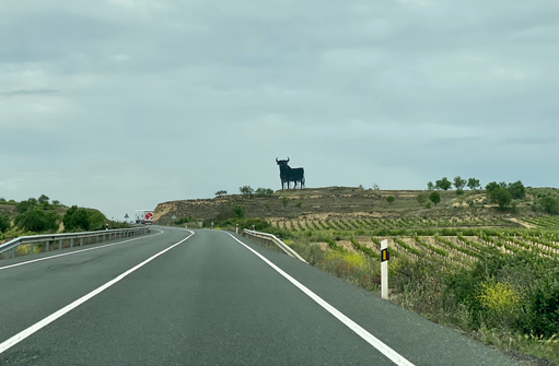 strada panoramica della Rioja con pannello di toro all'orizzonte e vigneti