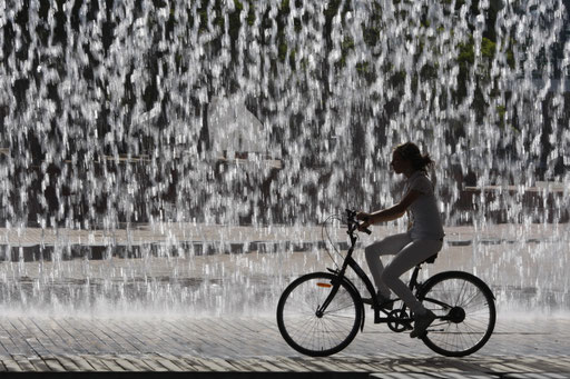 A woman rides her bike past a water display in Lisbon July 2, 2009.