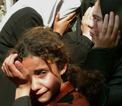 The sister of four-year-old Palestinian girl Elham al-Assar and other relatives cry inside their home at the Nuseirat refugee camp in the central Gaza Strip during her funeral on March, 2003