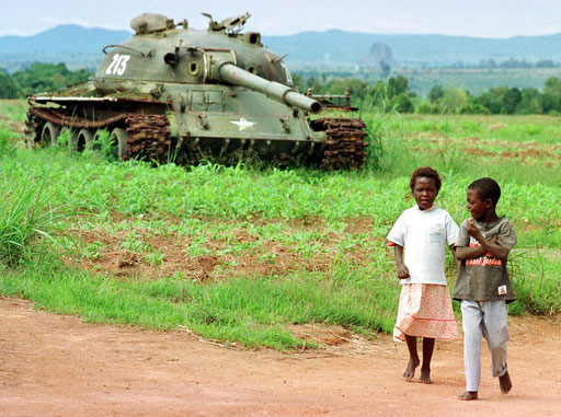 Kids walk past a abbandoned armoured car in Angola on November 1995