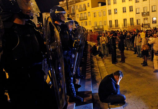 Man seated in the Parliament steps in front of the riot policemen protests against new 2013 state budget in Lisbon October 15, 2012.