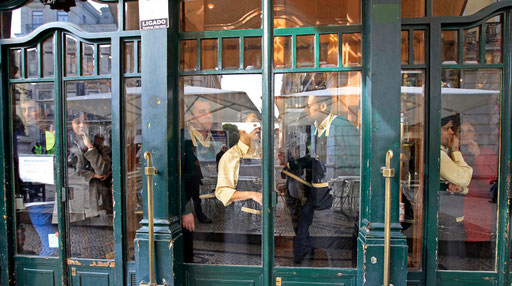 Customers and waiters watch behind closed doors the march to the Portuguese parliament in Lisbon during a protest against austerity November 14, 2012.