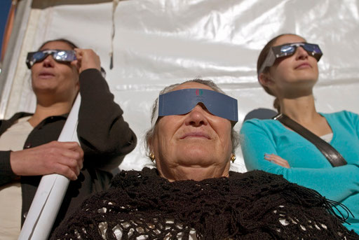 Grandmother mother and daughter watch the annular solar eclipse in Arguzelo with diferent artifacts near the Portuguese Northern city of Braganca October 3, 2005.