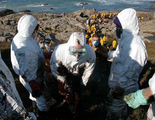 Volunteers make a human chain to help each other and carry pails full of oil from the coast line in Porto Mougas village on the northwestern Spain province of Galicia after the oil spilled from the Prestige tanker on December, 2002