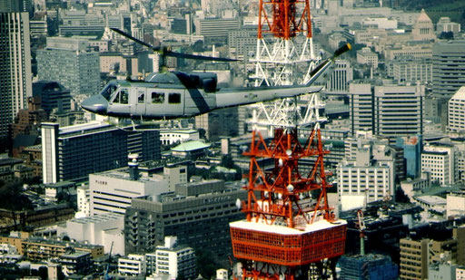 Carrying the commander of US Forces, Japan, a UH-1 from Yokota Air Base passes the red and white skeletal spire of Tokyo Tower.