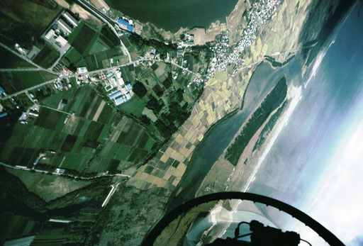 Seen from the cockpit, the world turns upside down as an F-16 bores in for a gunnery pass on the Ripsaw Range in northern Japan. The targets are the aligned whitish rectangles in the cleared swath visible just above the curved canopy bow.