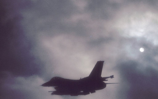 Silhouetted as it cuts through low late-afternoon clouds, a Misawa-based F-16 approaches the Ripsaw gunnery and bombing range for a low-level surface attack pass.