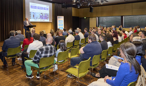 Blick von schräg hinten auf den vollen Saal während der Präsentation