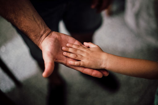 Ein Kind gibt seinem Vater die Hand. Systemische Gedanken zum Vatertag.