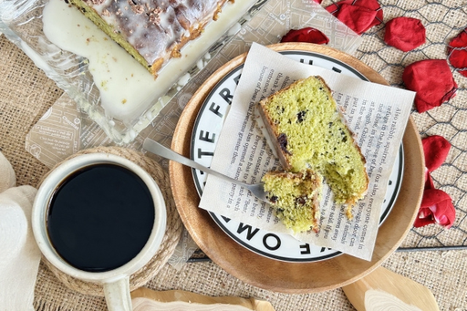 英文資料ペーパーのうえに食べかけのパウンドケーキ。コーヒーの入ったマグカップ。