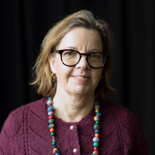 Porträt von Constanze Farzaie aus dem Vorstand des Netzwerk Gewaltfreie Kommunikation Darmstadt. Sie hat kinnlange braune Haare, träg Brille und einen violetten Pullover und eine Kette mit großen bunten Perlen. Sie schaut interessiert und freundlich.