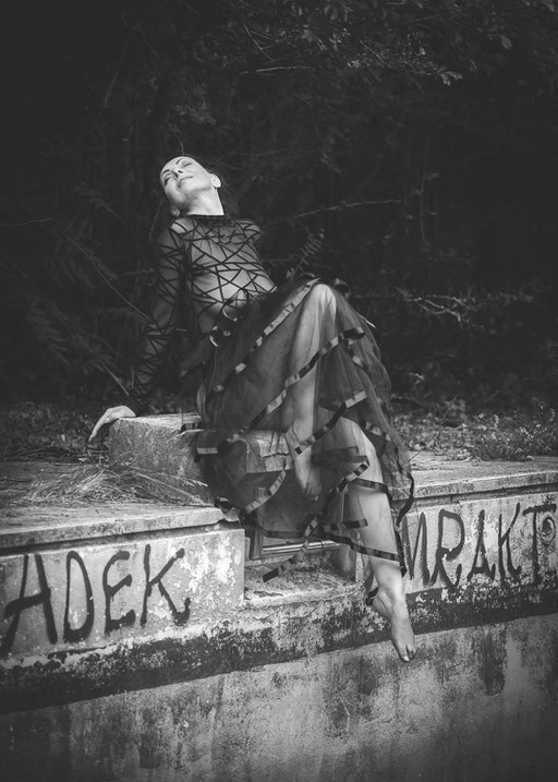 Sinnliche Schwarzweißfotografie einer Frau in eleganter Haltung auf urbaner Location, künstlerische Erotikfotografie im Raum Villach, Kärnten, mit natürlichem Licht.