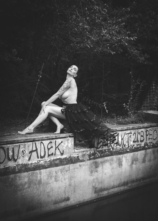 Stilvolle Aktaufnahme einer Frau in natürlicher Umgebung, sitzende Pose mit Fokus auf Körperlinie und Ausdruck, hochwertige Erotikfotografie in Kärnten, Region Villach.