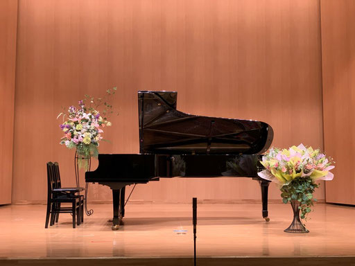 写真左側はレンタルステージフラワー、ピアノ前面右側は生花ブーケスタンドフラワーの装花です