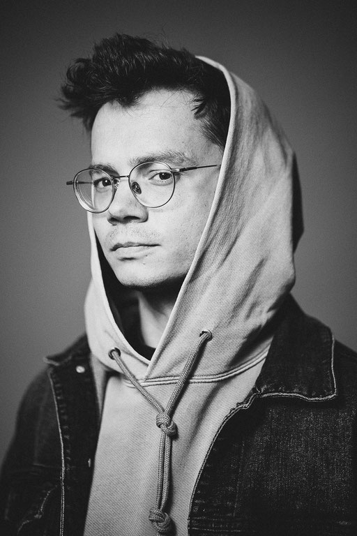 Junger Mann mit Kapuze und Brille in Studio Beleuchtung. Porträt Foto aufgenommen von Sebastian Schieder