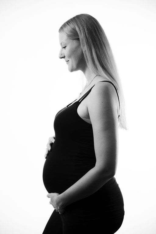 Schwangere Frau im Profil mit Babybauch.