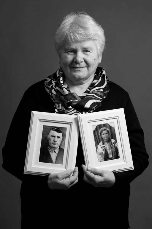 Frau mit zwei gerahmten Fotos in der Hand in Fotostudio. Aufgenommen von Sebastian Schieder Porträt Fotograf Regensburg.