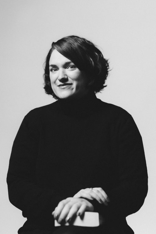 Studio Porträt von schwarz gekleideter Frau mit Buch. Aufgenommen von Sebastian Schieder Porträt Fotograf Regensburg.