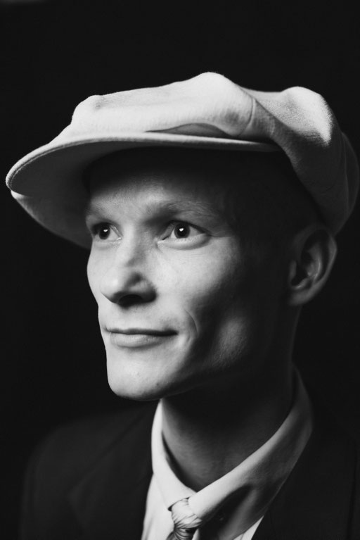 Mann mit großer altmodischer Mütze in dramatischer Studio Beleuchtung. Porträt Foto Regensburg.