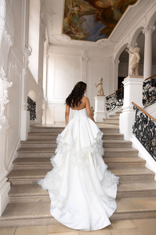 Junge Frauauf einer Treppe trägt das Brautkleid Christina aus der Amo&Luv Kollektion